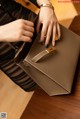 A woman holding a brown handbag on a wooden table.