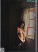 A naked woman standing in front of a window.