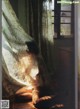 A woman sitting on the floor in front of a window.