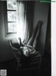 A woman laying in a wicker chair in front of a window.