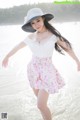 A woman in a white top and pink skirt on the beach.