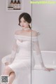 A woman in a white dress sitting in a bathtub.