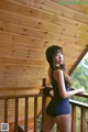 A woman in a black bathing suit standing on a balcony.