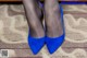 A close up of a woman's legs wearing blue shoes.