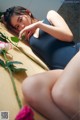 A woman laying on a bed next to a pink rose.