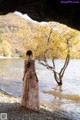 A woman in a long dress standing in the water.