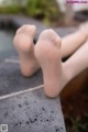 A close up of a person's bare feet on a concrete ledge.