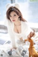 A woman in a white sweater is posing with a reindeer.