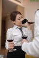 A woman in a uniform drinking a glass of wine.