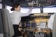 A woman sitting in the cockpit of an airplane pointing at something.