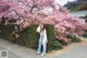 A woman standing in front of a flowering tree.