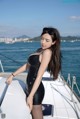 A woman in a black bathing suit standing on a boat.