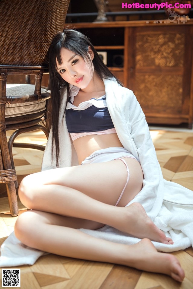 A woman sitting on the floor in a white robe.