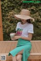 a woman sitting on a wooden bench wearing a straw hat