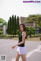 A woman in a black top and white shorts walking down a street.