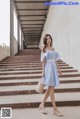 A woman in a blue and white dress is walking up some stairs.