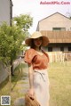 A woman wearing a straw hat standing in the grass.