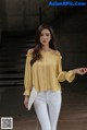 a woman wearing white jeans and a yellow blouse