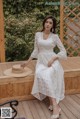 a woman in a white dress sitting on a wooden bench