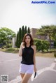 A woman in white shorts and a black top is walking down the street.