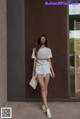 a woman standing in front of a door wearing a white t - shirt