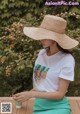 a woman wearing a white t - shirt and a straw hat