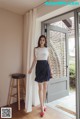 a woman standing in front of a door wearing a white top and black skirt