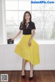 A woman in a black shirt and yellow skirt posing for a picture.