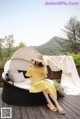 A woman in a yellow dress sitting on a wicker chair.