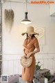 A woman wearing a brown dress and a straw hat.