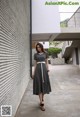 A woman in a black and white striped dress is walking down a sidewalk.