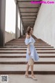 A woman in a blue and white striped dress is standing on some steps.