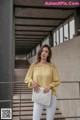 a woman in white jeans and a yellow blouse posing for a picture