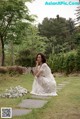 A woman in a white dress sitting on a stone path.