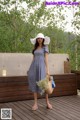 A woman wearing a blue dress and a white hat.