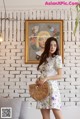 a woman standing in front of a white brick wall