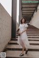 a woman in a white dress is walking down some stairs