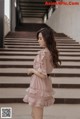 a woman in a pink dress standing on some steps