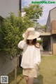 A woman wearing a white blouse and a straw hat.