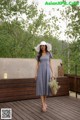 A woman standing on a wooden deck holding a basket of flowers.