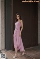 a woman standing in front of a door wearing a pink dress