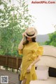 a woman wearing a yellow dress and a straw hat