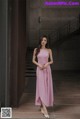 a woman in a pink dress standing in front of a wall