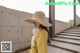 a woman wearing a yellow shirt and a straw hat