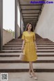 a woman in a yellow dress standing on some steps