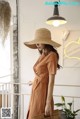 a woman wearing a brown dress and a straw hat