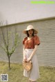 A woman wearing a straw hat standing in front of a wall.