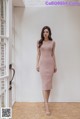 a woman standing in front of a door wearing a pink dress