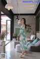 a woman in a green and white dress standing in a room