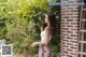 A woman standing next to a brick wall holding a plant.